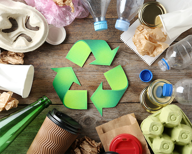 Recycling-Symbol und verschiedene Abfälle auf Holzuntergrund, Draufsicht